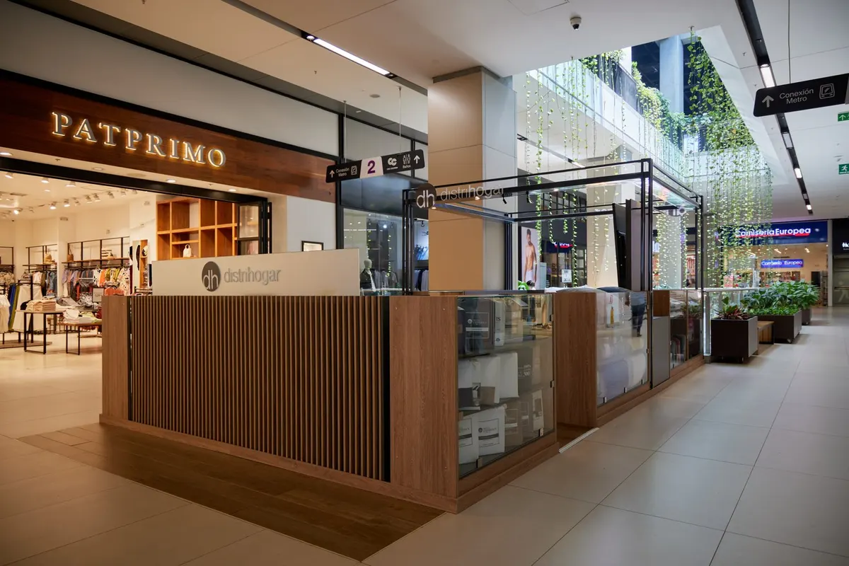 Kiosco Distrihogar en Viva Envigado: recepción de madera, vitrinas y estructura metálica en el atrio del centro comercial